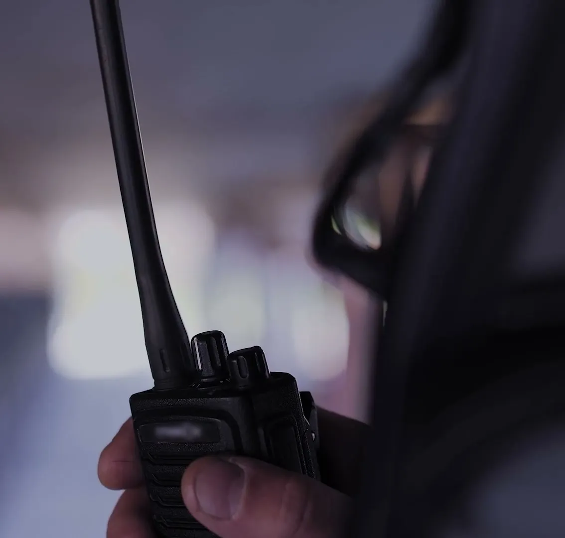 A field operator holding a two-way radio.